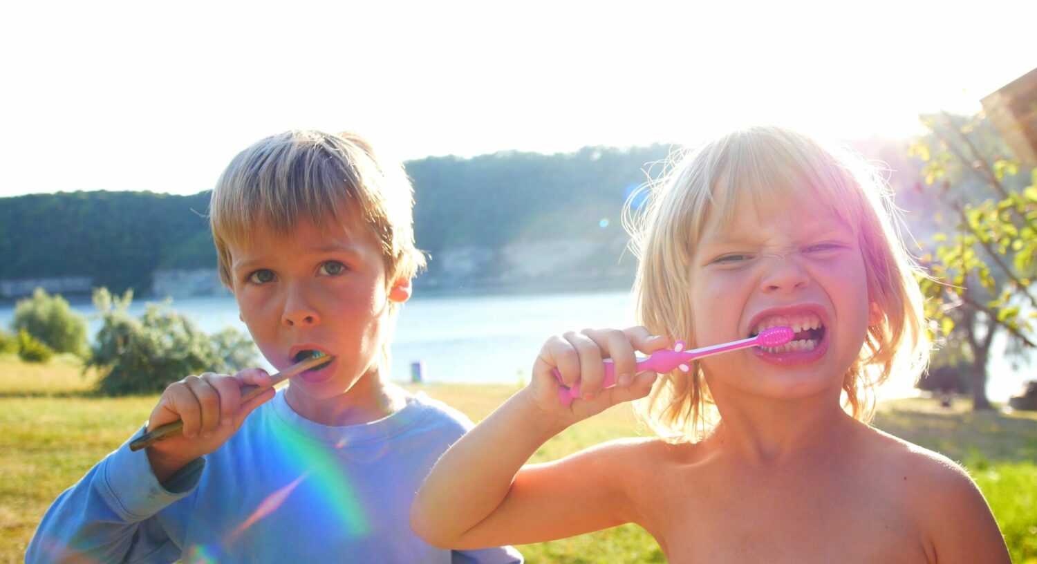 Niño y niña cepillándose los dientes al aire libre | Salud Bucodental | Caries | Dentista Madrid Río