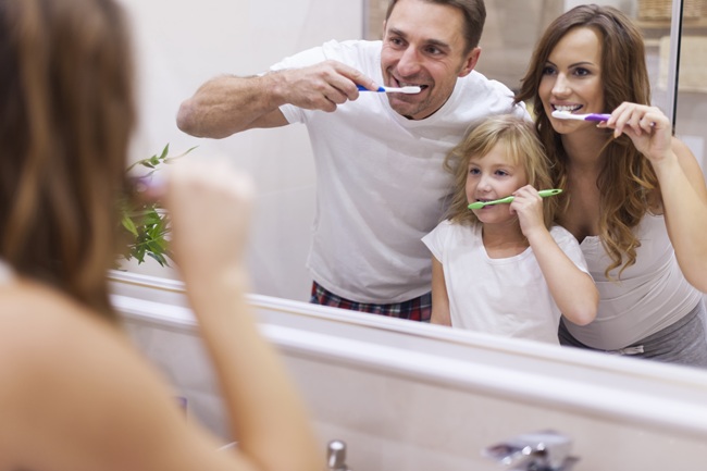 Familia limpiándose los dientes mientras se mirar al espejo | Buenos Hábitos Dentales | Boca Sana | Clínica Dental en Madrid | Clínica dental Legazpi