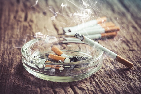 Cenicero con colillas y un cigarro encendido | Encías que sangran | Salud Bucodental | Problemas Dentales