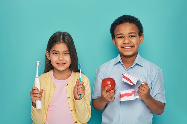 Dos niños agarrando cepillo de dientes y fruta | revisiones dentales infantiles | Clínica Dental Madrid Río | Clínica Larrañaga | Vuelta al Cole