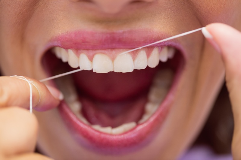 Mujer limpiandose los dientes con hilo dental | Cuidado de las Encías | Salud Periodontal | Clínica Dental Madrid
