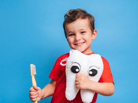 Niño agarrando un peluche en forma de muela y un cepillo de dientes | revisiones dentales infantiles | Clínica Dental Madrid Río | Clínica Larrañaga | Vuelta al Cole